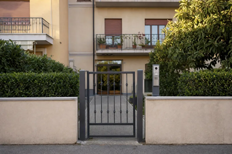 Il cancelletto pedonale di un palazzo con la colonnina del citofono accanto.
